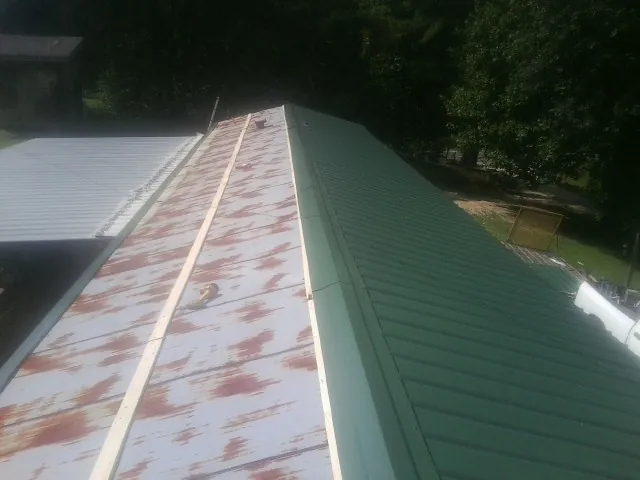 Old rusted panels beside newly installed green metal roofing — Wind Damage Roof Repair by Roofing Brothers in Log Lane Village