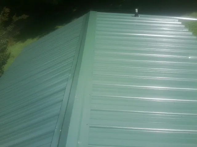 New green metal panels meeting at the ridge of a roof — Flat Roof Repair work by our crew in Log Lane Village