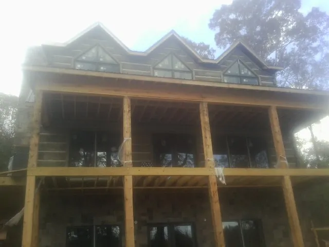 Dormers and porch framing on a large log home under construction — Roof Coating work by our crew in Log Lane Village
