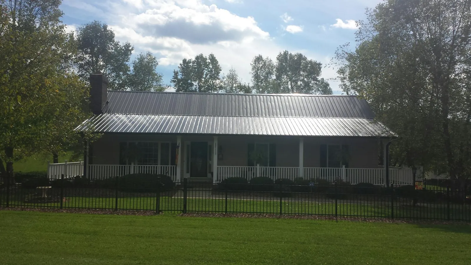 Gray metal roof on a brick ranch with a full width front porch — Gutter Guard Installation work by our crew in Log Lane Village