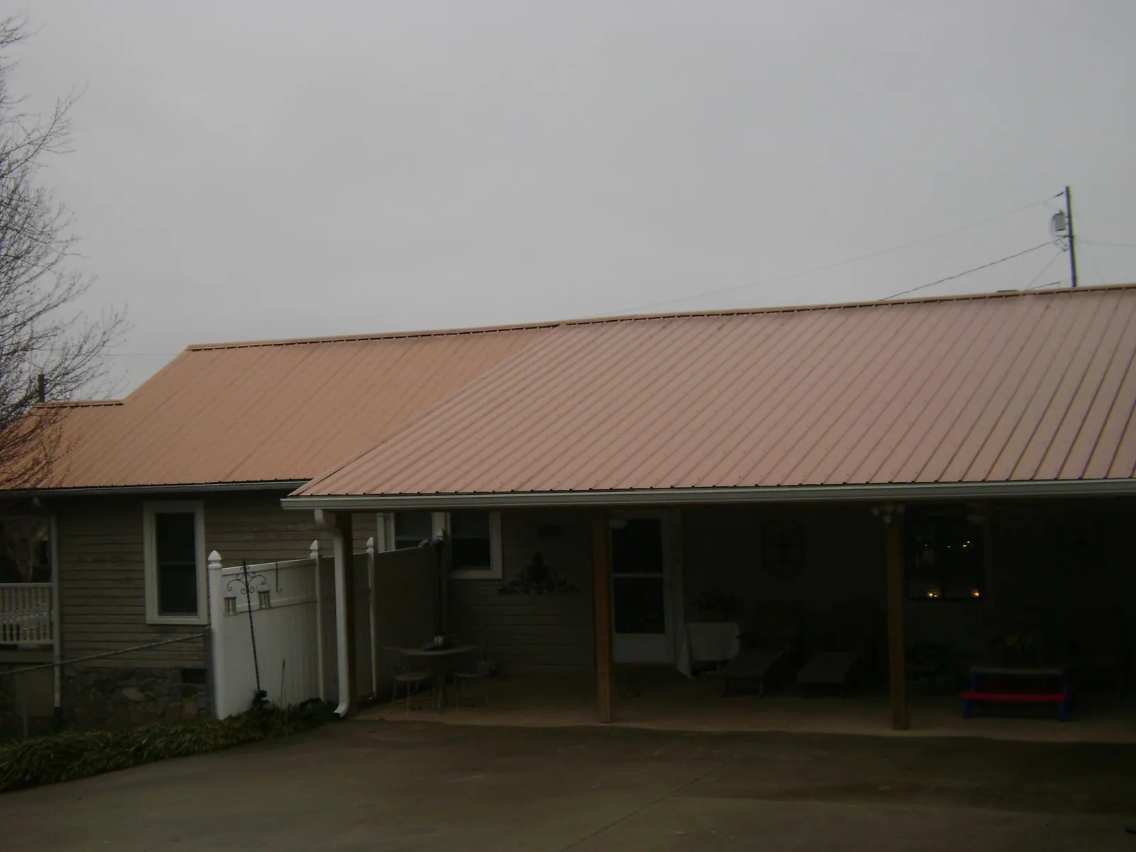Copper toned metal roof over a wide covered patio in Log Lane Village