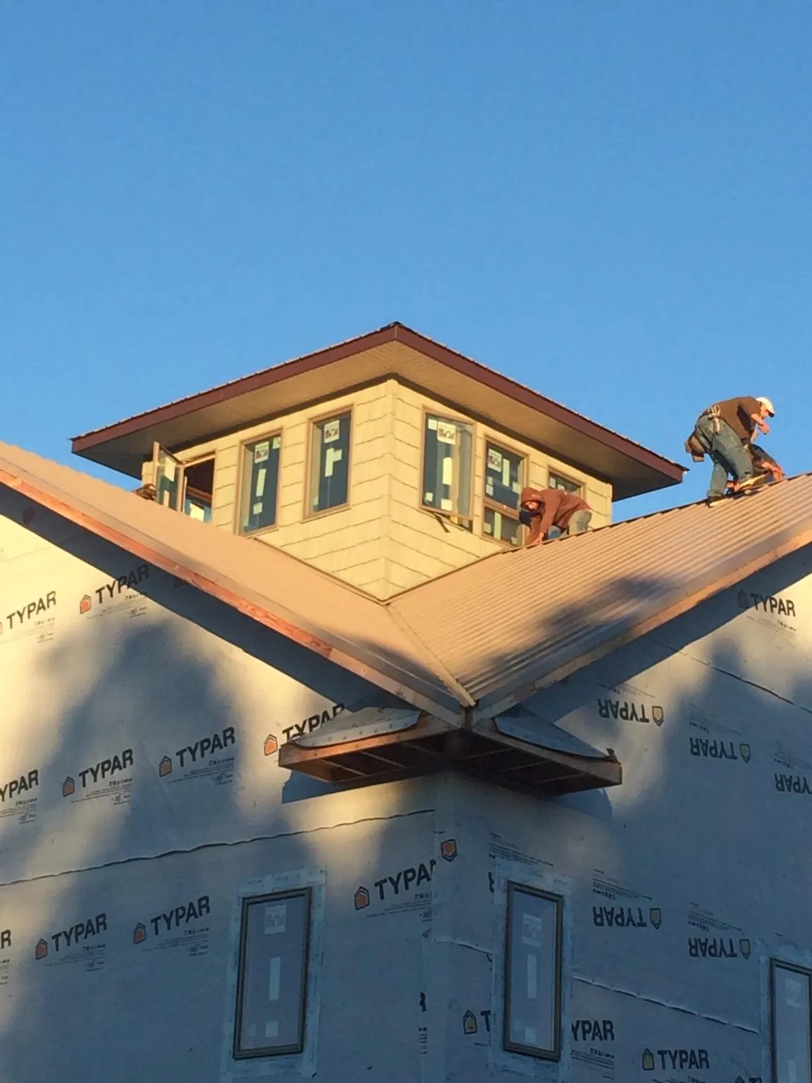 Roofers working around a rooftop cupola on a new metal roof at sunset — Roof Waterproofing in Log Lane Village by Roofing Brothers